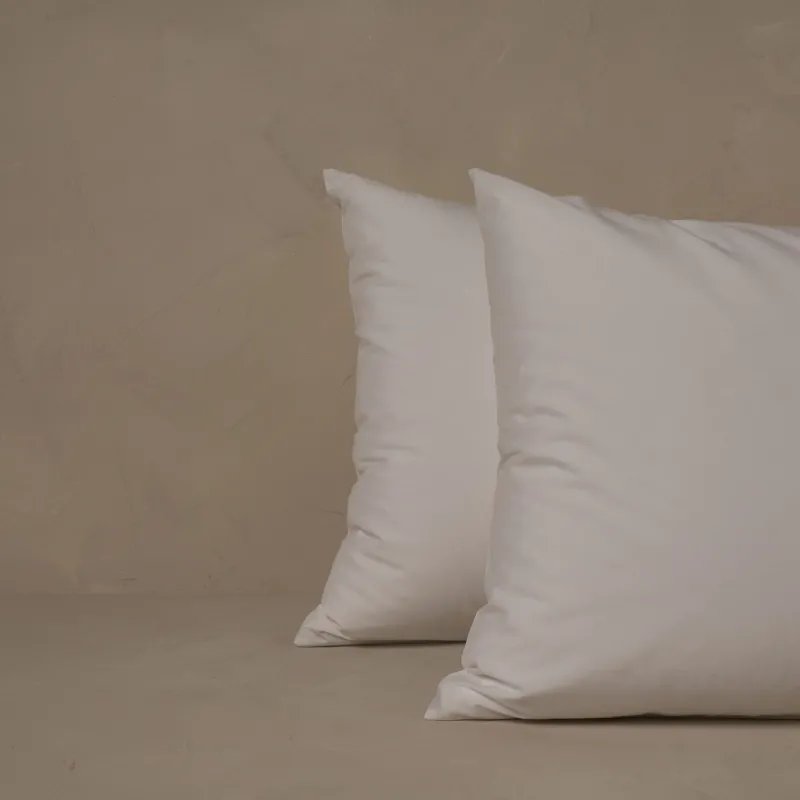 Two pillows stacked one in front of the other. The pillow cases are made of LETTO Americano Cotton Percale in color white.