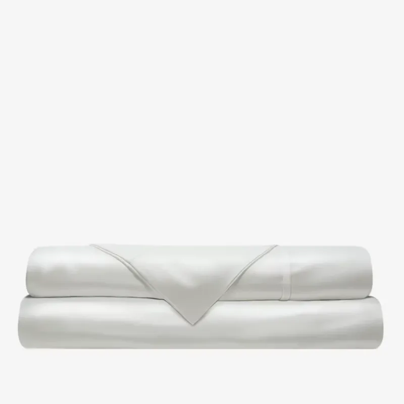 Folded ivory sateen fitted sheet stacked with flat sheet, smooth lustrous finish visible.